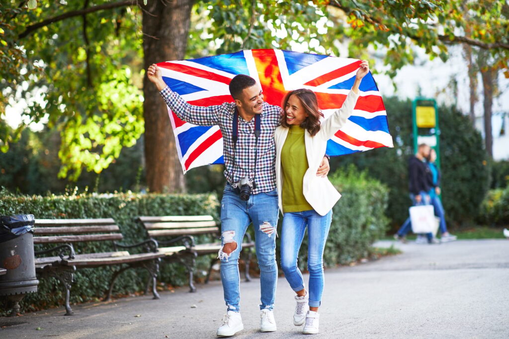 Happy young couple of tourists with a UK flag