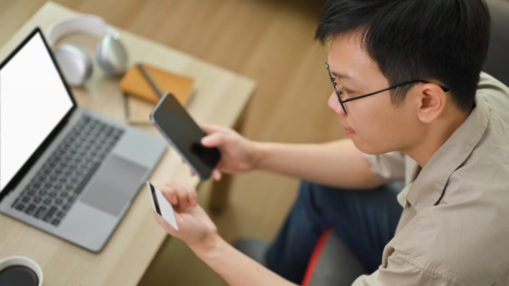 Man holding smartphone and credit card making online payment or shopping online form home.